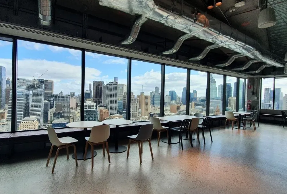 Commercial floor beneath tables and chairs in a city-facing breakout space