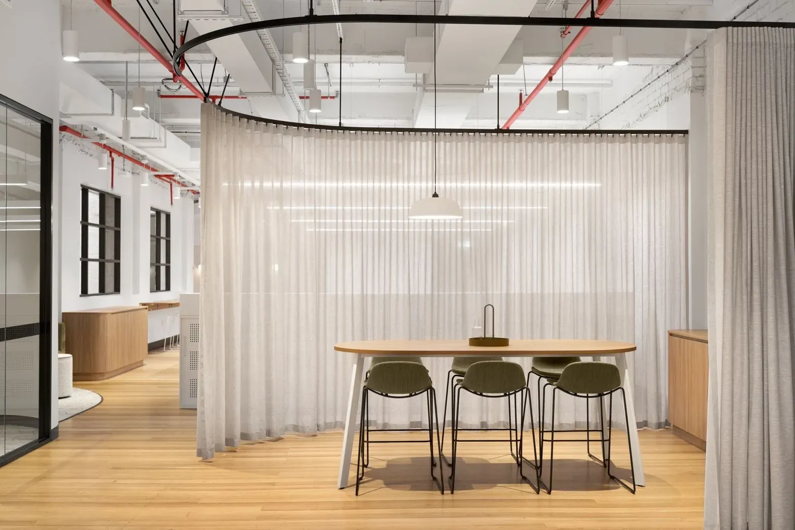 Meeting room with timber-look flooring, green chairs and a round table